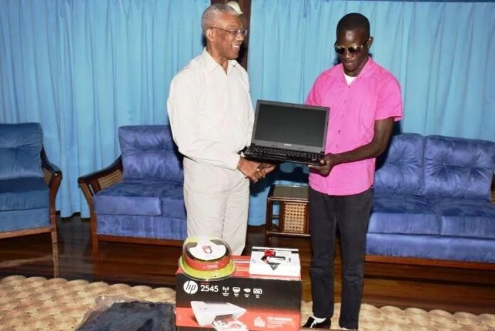 President David Granger handing over the laptop and other equipment to 18-year old Ceion Rollox